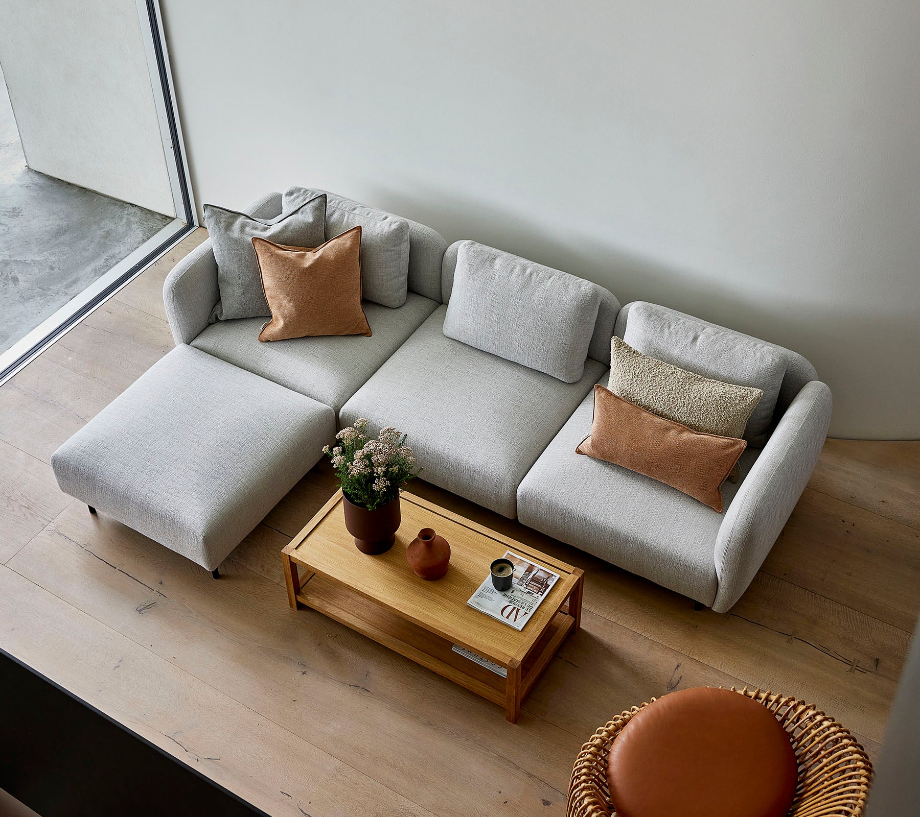 En stilfuld lysegrå sektion sofa med puder, parret med et rundt trækaffebord og en rund siddeplads, der skaber en hyggelig atmosfære.