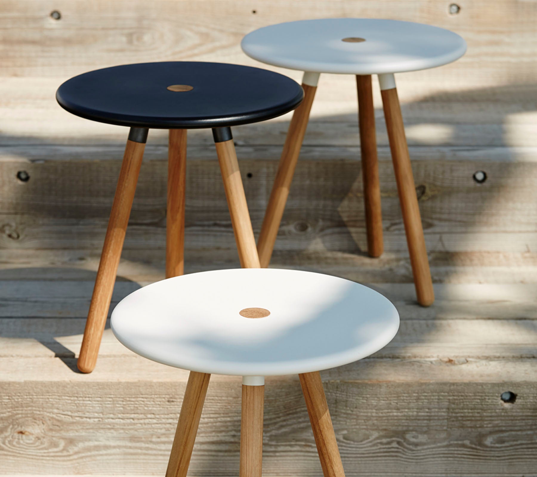 Tre minimalistiske st stools med runde toppe i sort og hvid, hver støttet af træben, der viser et moderne og stilfuldt design.