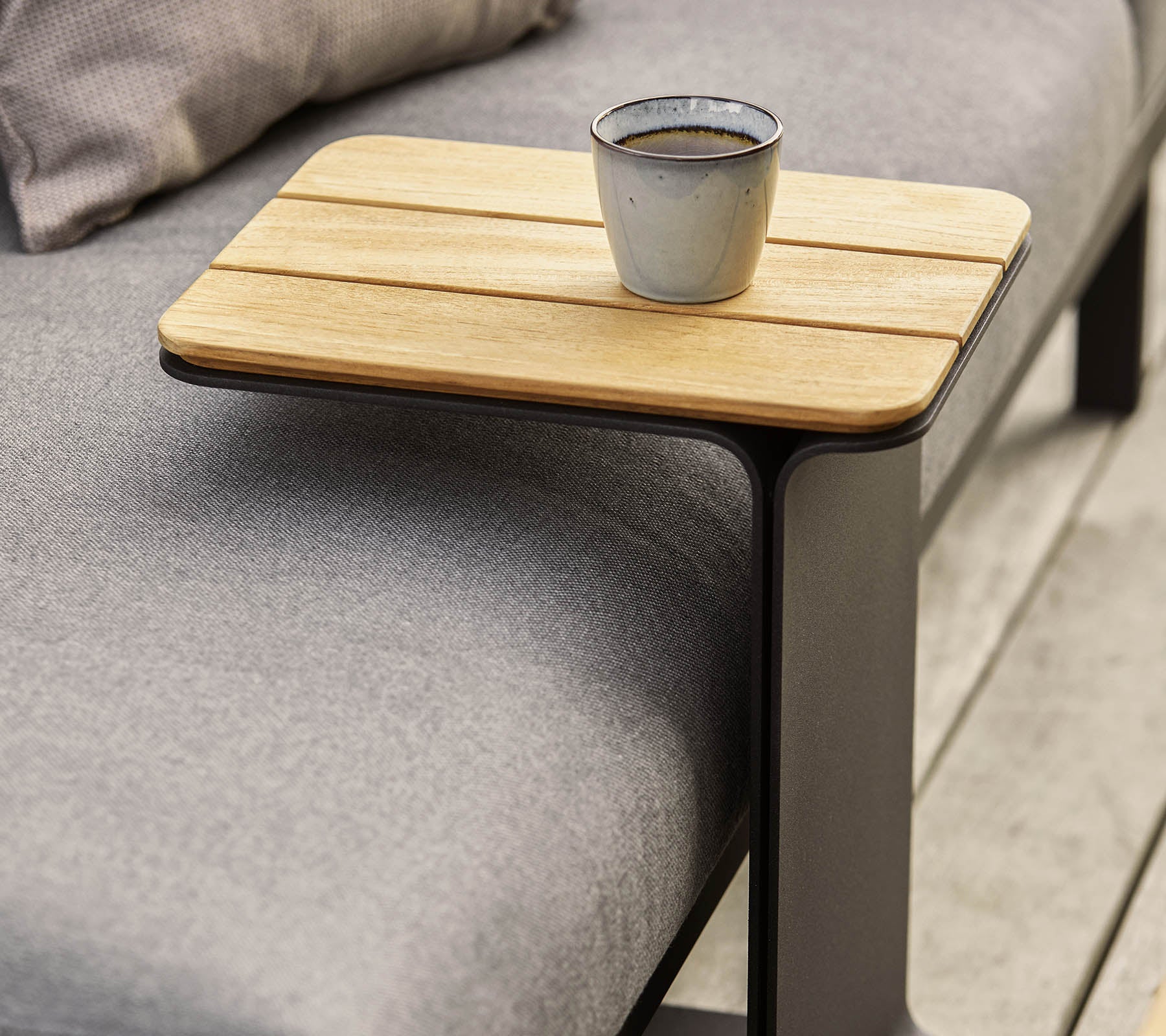 Et slankt sidebord med en trætop og en moderne metalramme, med en lille kop placeret på det.