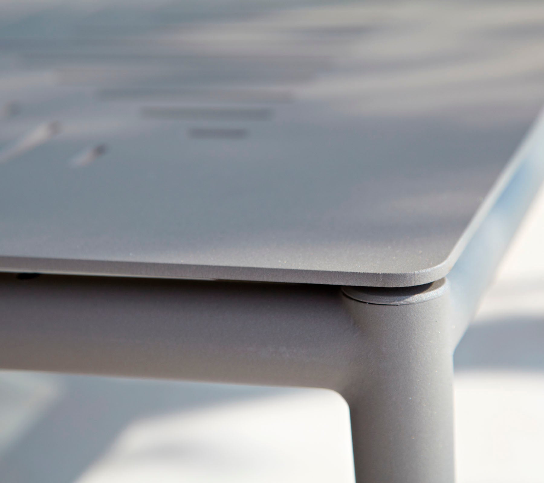 Nærbillede af et elegant, moderne bord med en glat overflade og subtile detaljer. Designet fremhæver rene linjer og minimalistisk stil.