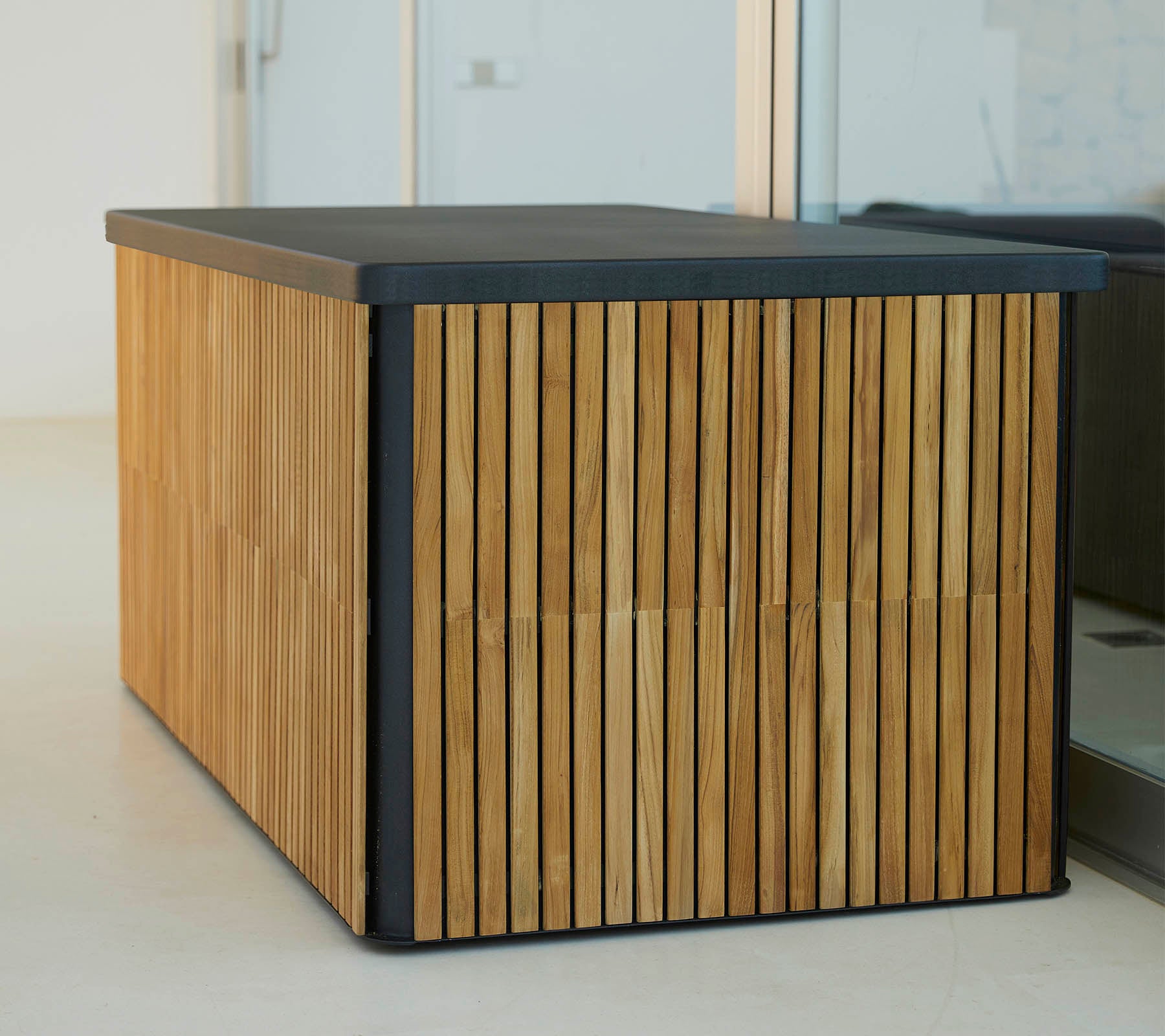 Et moderne træbord med lodrette lameller på siderne og en slank, mørk top, der tilbyder et stilfuldt og funktionelt design.