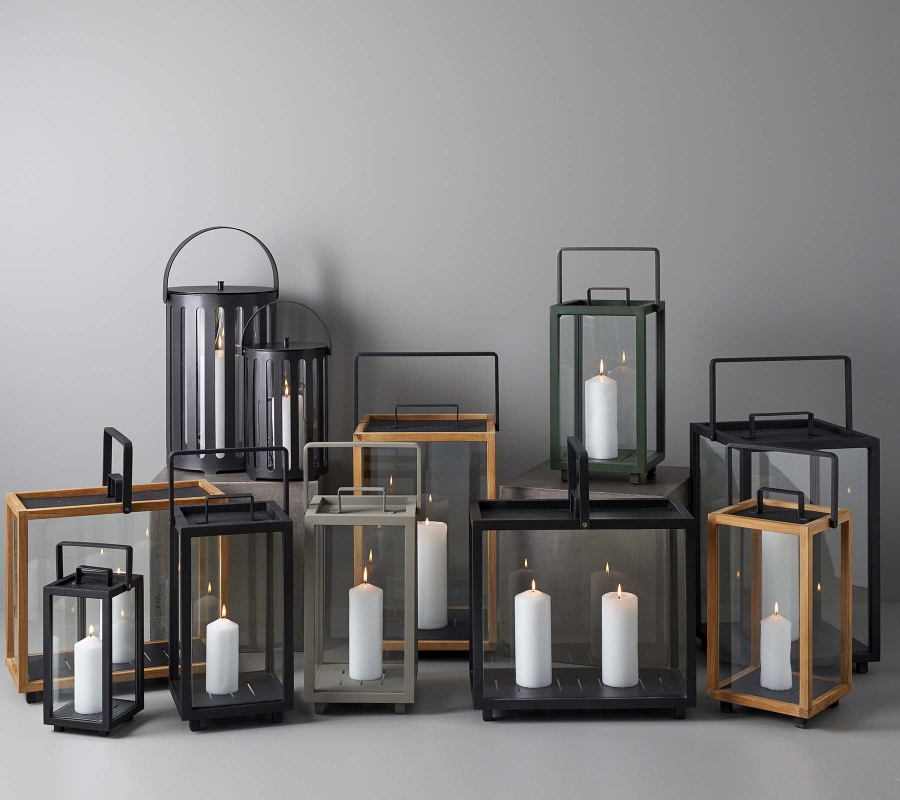En samling af elegante lanterner i forskellige størrelser og stilarter, der har stearinlys indeni, arrangeret sammen på en neutral baggrund.