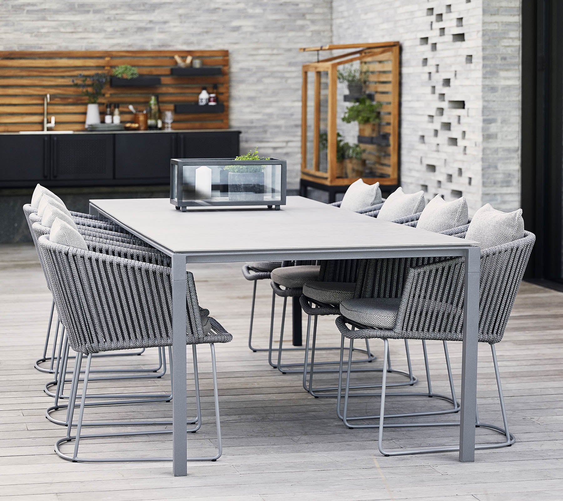 Et moderne spisebord med grå metalramme og komfortable stole, der har bløde puder og et minimalistisk design, perfekt til sammenkomster.