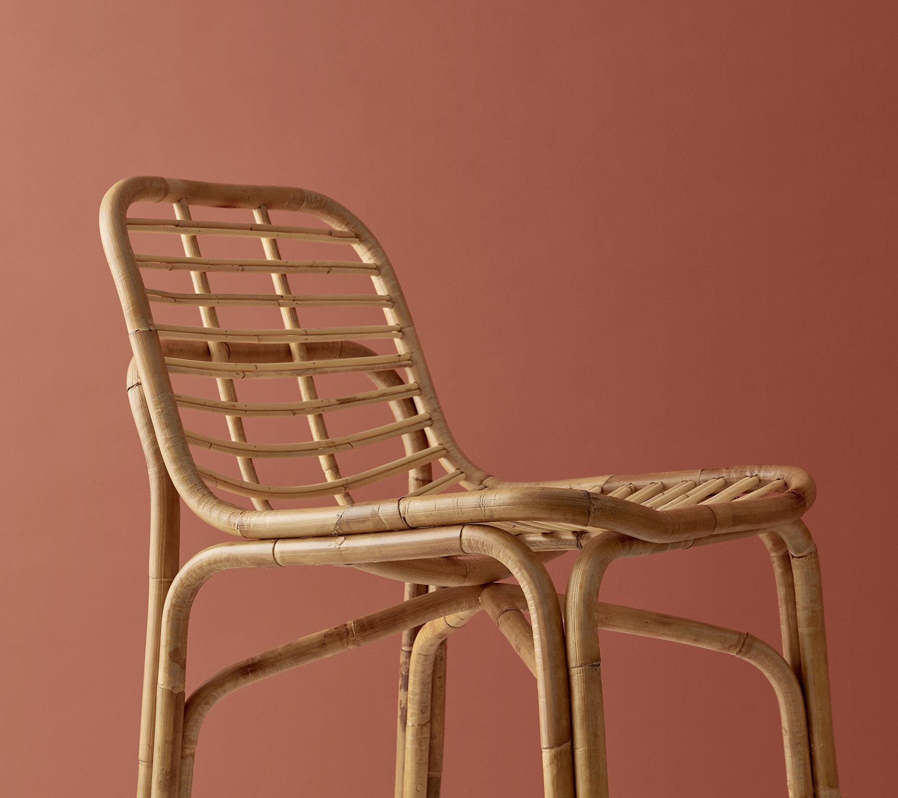 Stilfuld vævet stol i en naturlig finish med et minimalistisk design mod en afdæmpet baggrund.