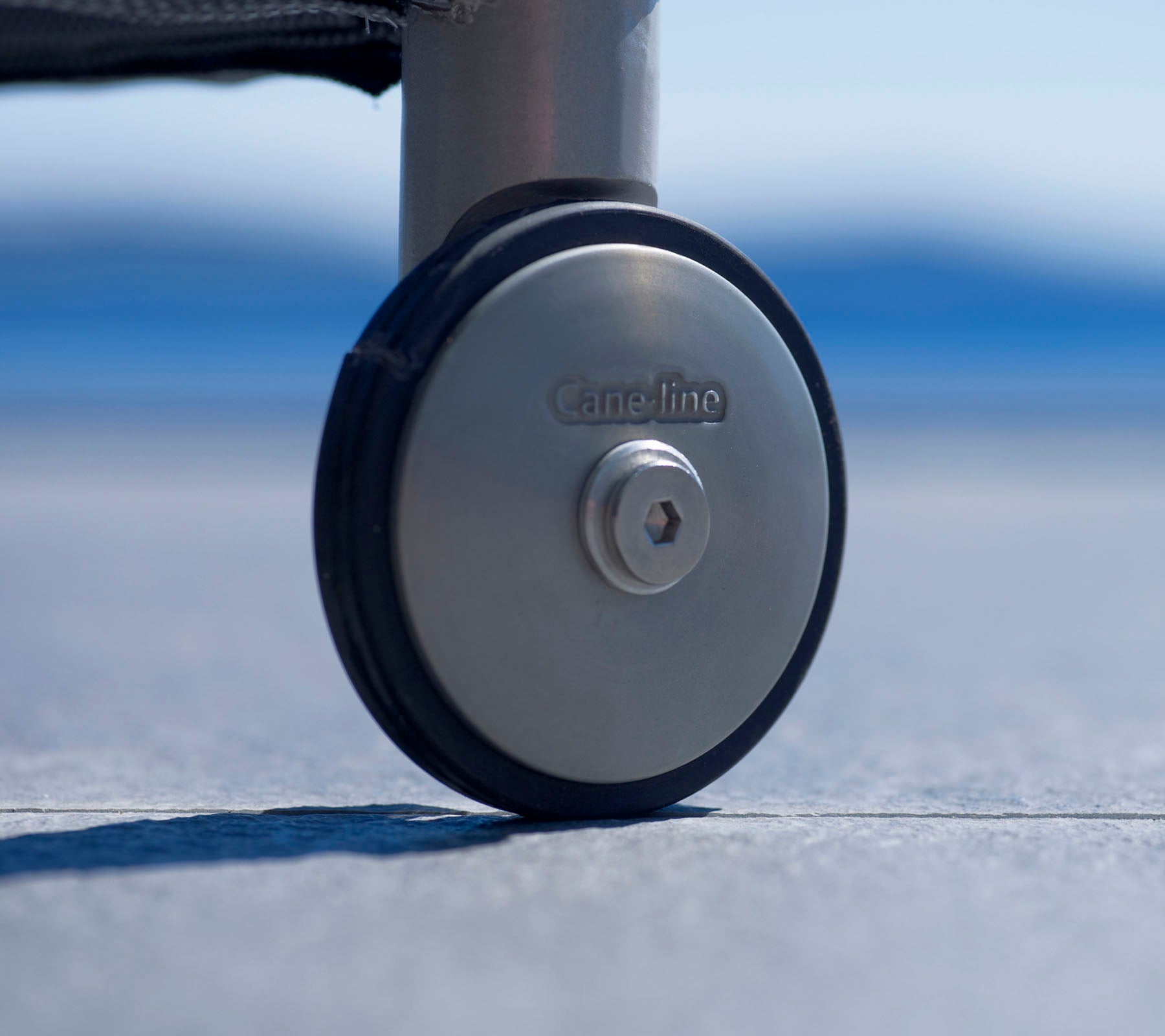Nærbillede af et holdbart hjul med metalfinish og et logo, designet til nem mobilitet og stabilitet på forskellige overflader.