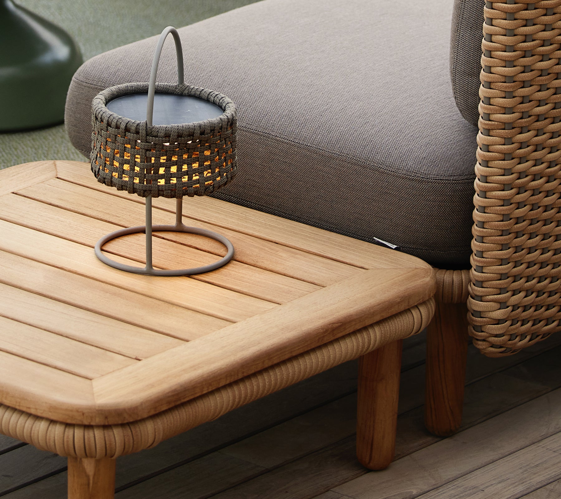 Teak kaffebord med en ribbet top, ledsaget af en vævet lampe, der skaber en hyggelig og indbydende atmosfære.