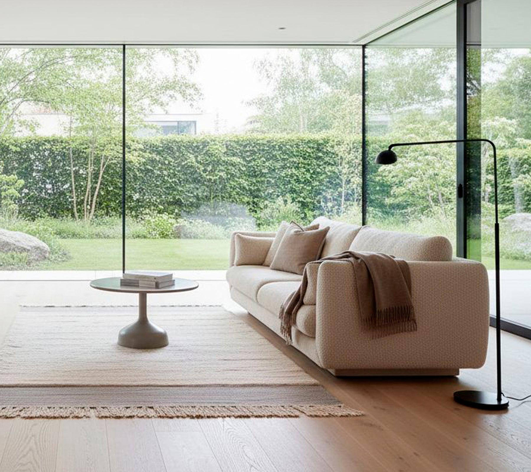 Moderne hvid sofa med en sort gulvlampe og rund sofabord i en minimalistisk stue.