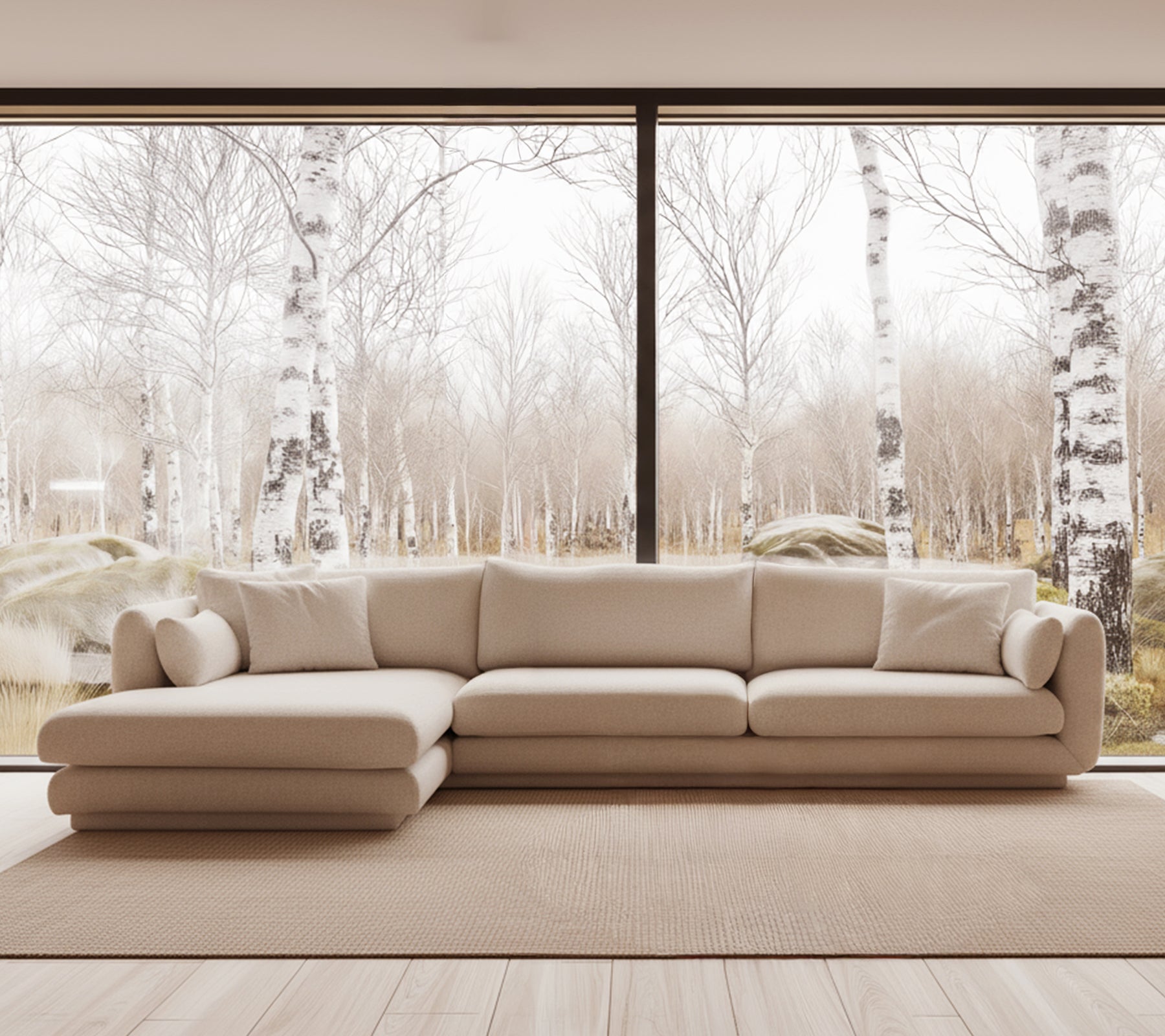 Beige moderne sofa i en lys stueindretning med store vinduer.
