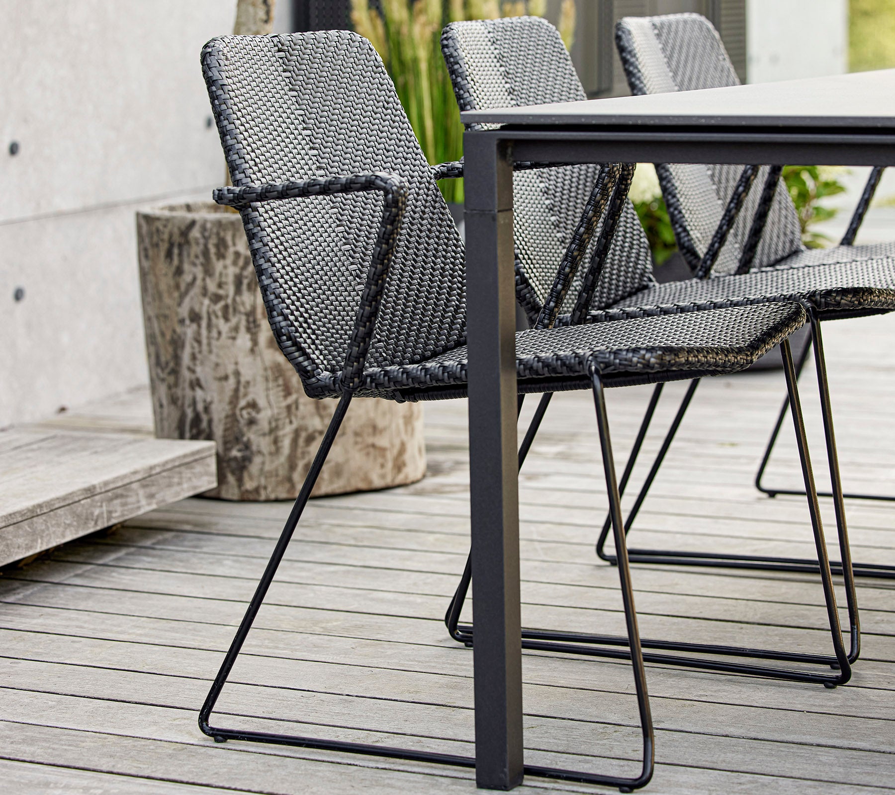 Et sæt af moderne sorte vævede stole placeret omkring et strømlinet bord, der viser nutidigt design og håndværk.