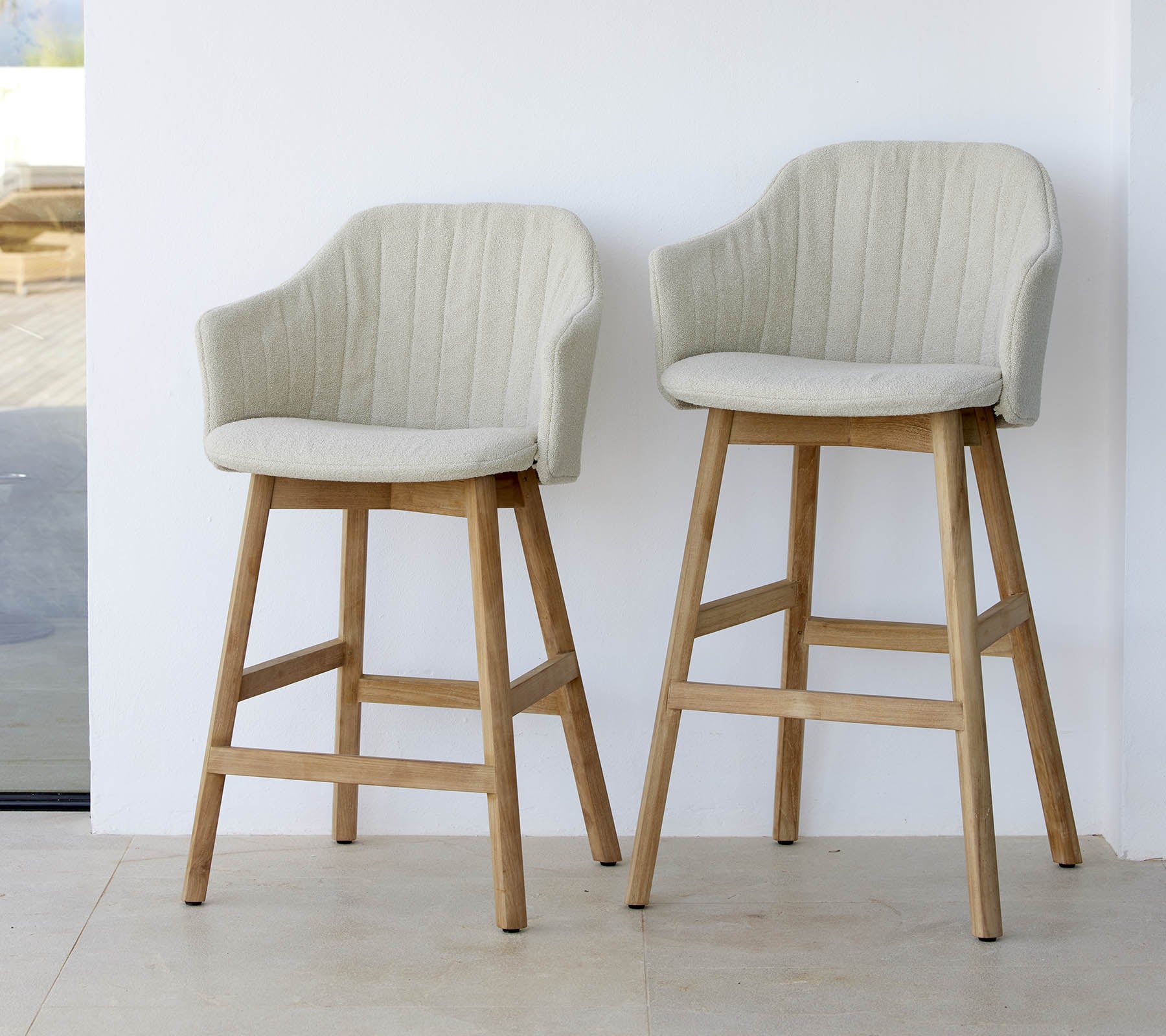 To stilfulde, lyse stole med buede rygge og træben, der viser et moderne og komfortabelt design.