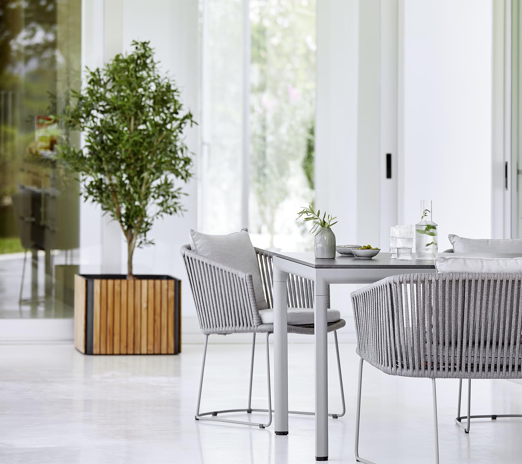 Et moderne spisestue med et slankt bord, teksturerede stole og en dekorativ potteplante, der skaber en stilfuld og indbydende atmosfære.