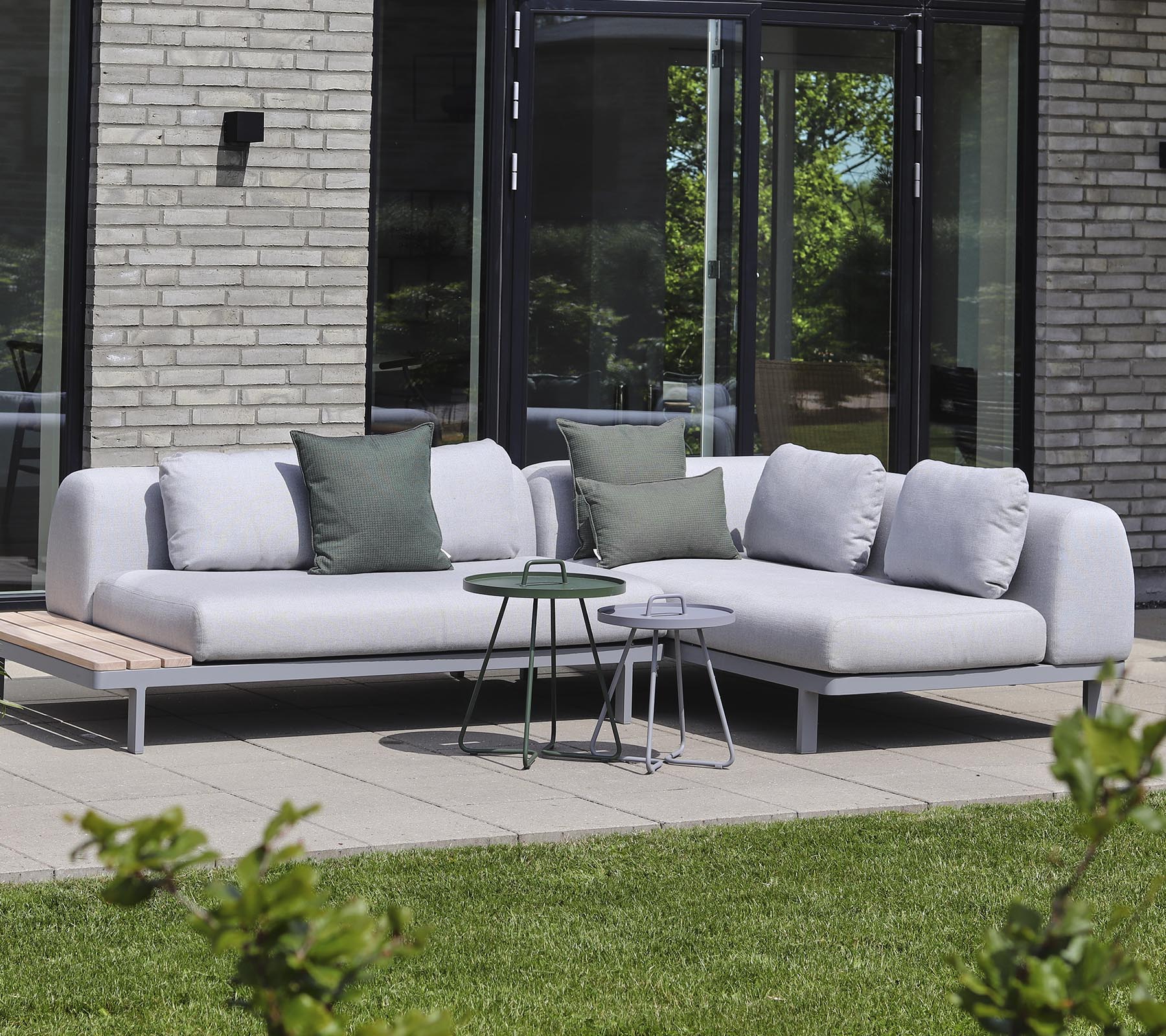 Moderne sektionelt sofa i lys stof med dekorative puder, parret med små sideborde i en rolig indstilling.