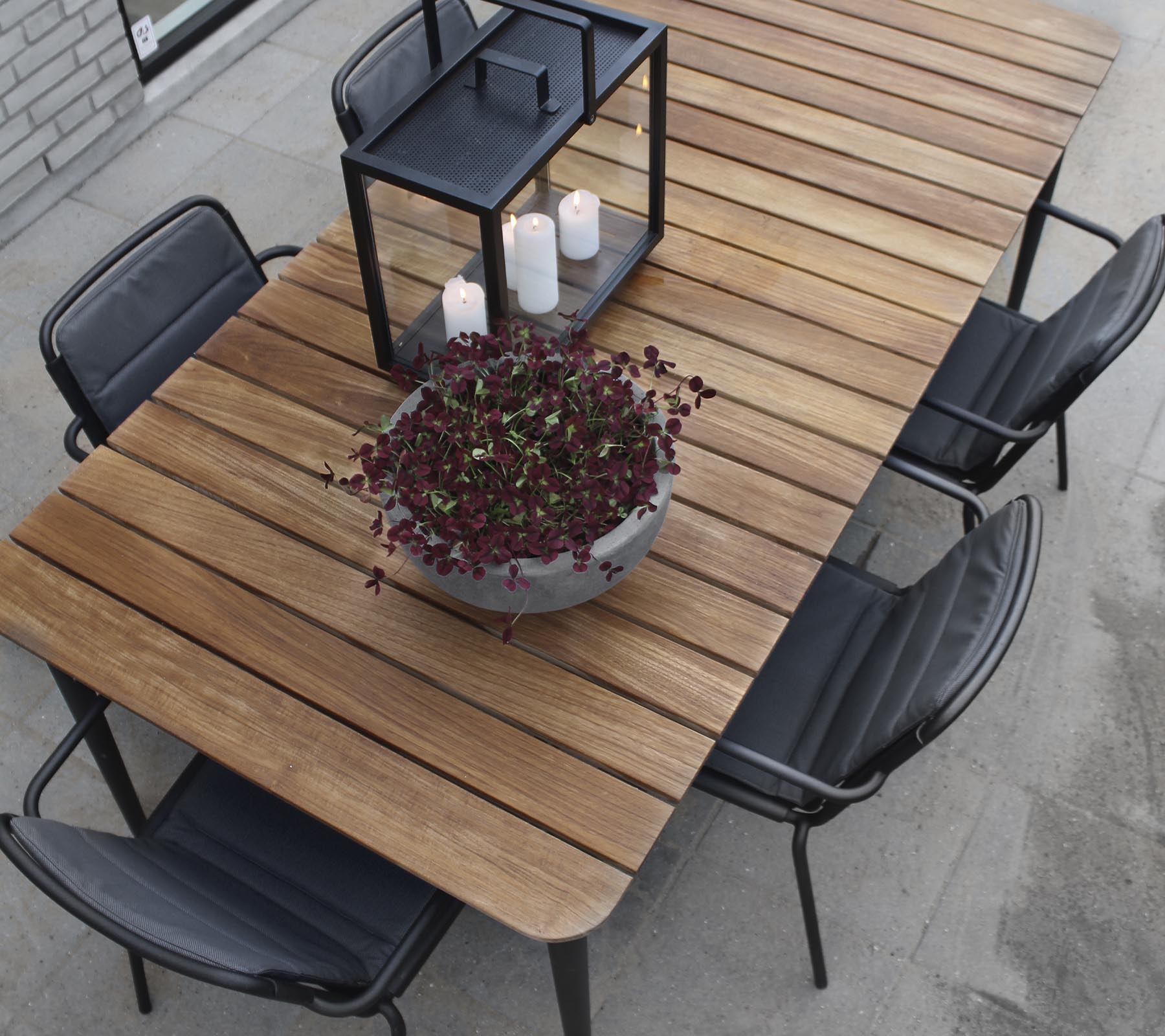 Et træbord med sorte stole, med en stor plantekrukke og et lysestage centerpiece.