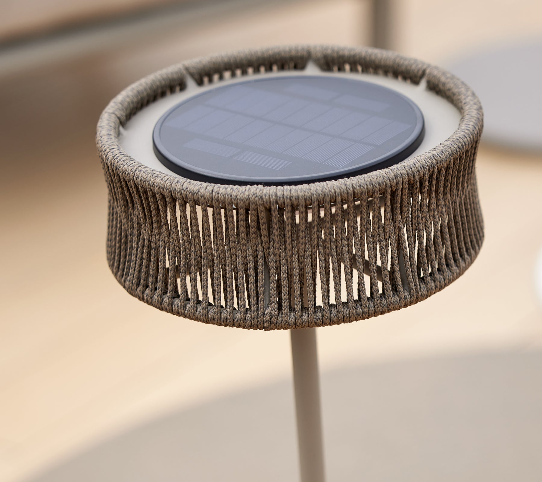En dekorativ LED-lampe med solpanel, prydet med et unikt vævet design, der skaber en illusion af elegance.