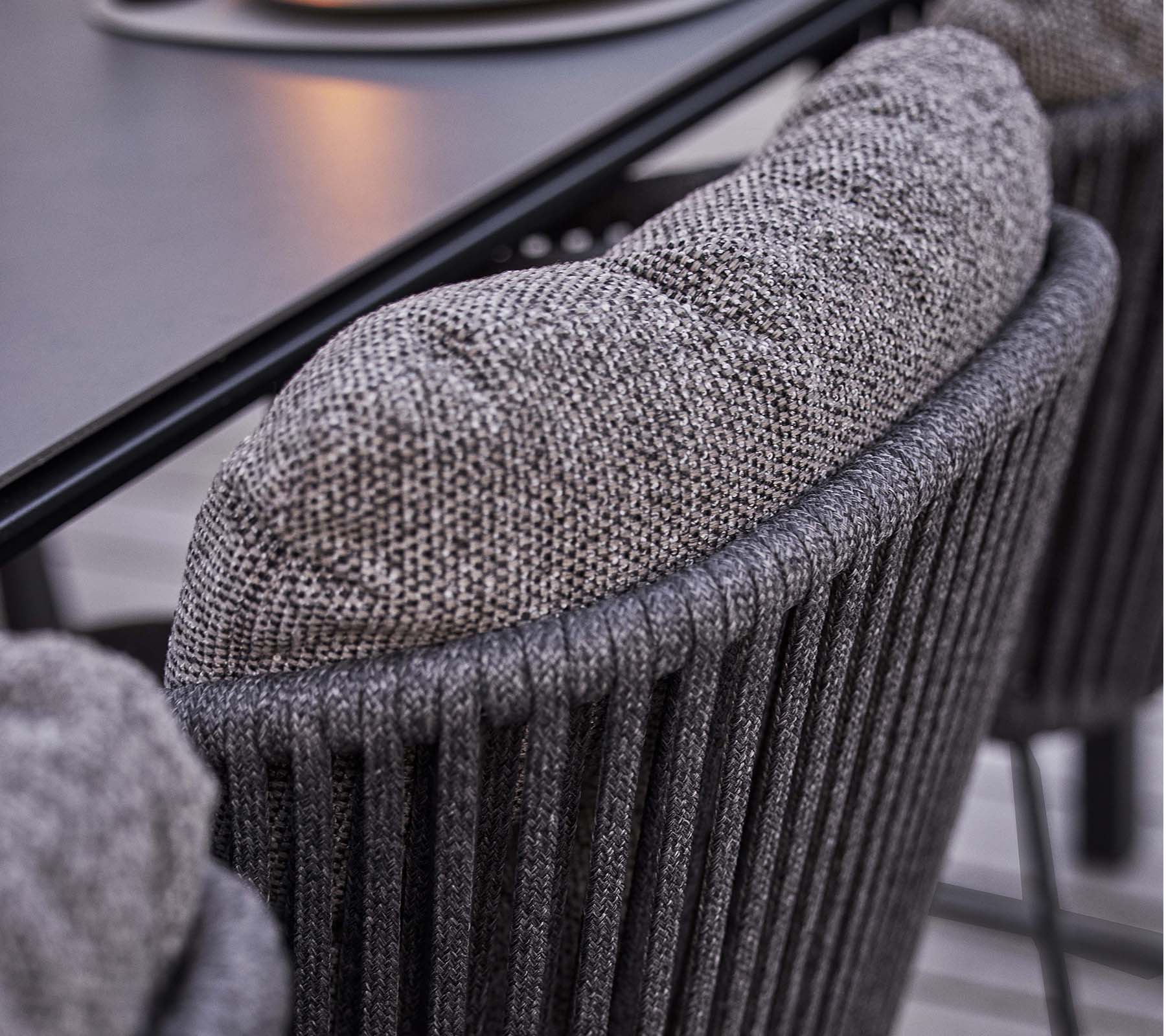 Nærbillede af et tekstureret stoleryg med en blød, polstret pude, der har et stilfuldt lodret ribbet design.