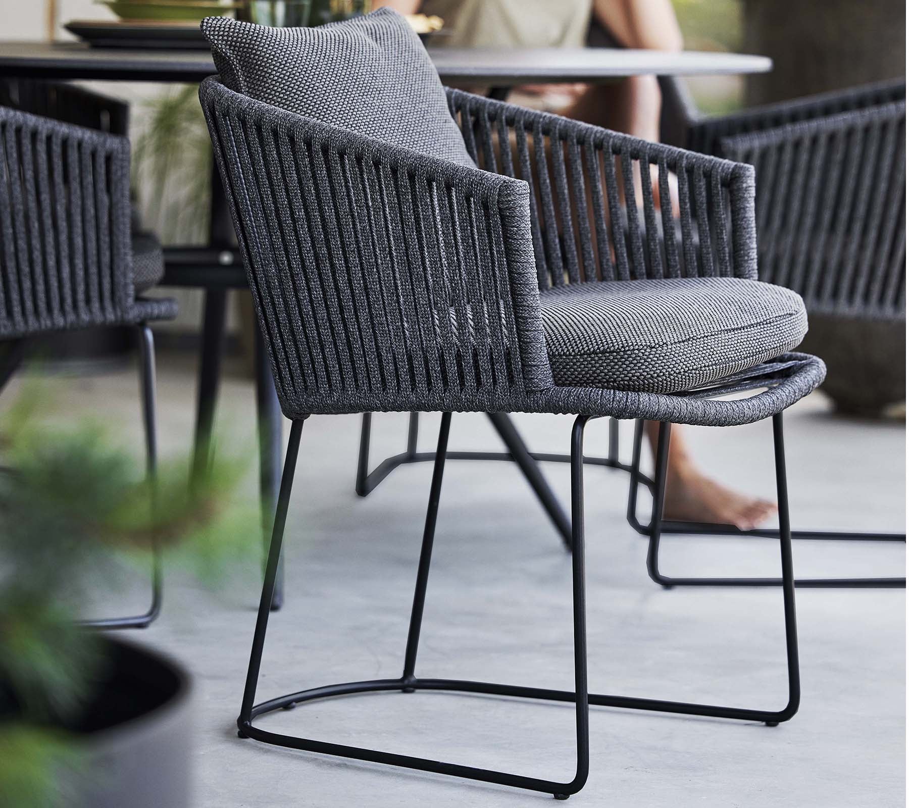 Stilfuld stol med et vævet design og blød pude, understøttet af en slank metalramme, perfekt til moderne rum.