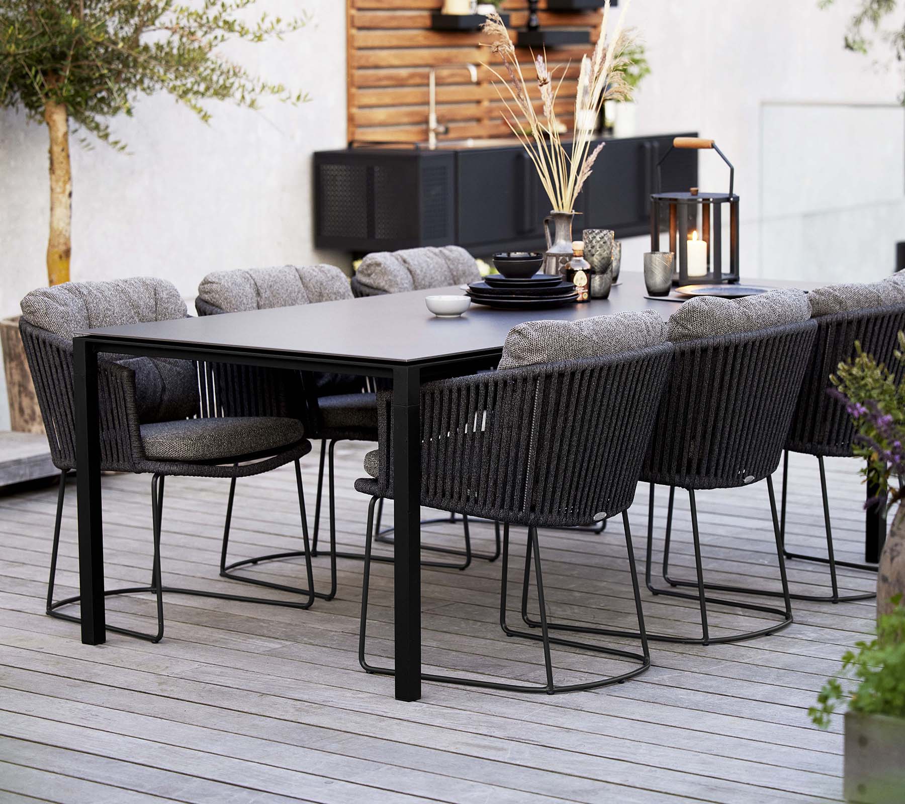 Et stilfuldt spisestueopsætning med et elegant bord omgivet af komfortable vævede stole, prydet med dekorative elementer og planter.