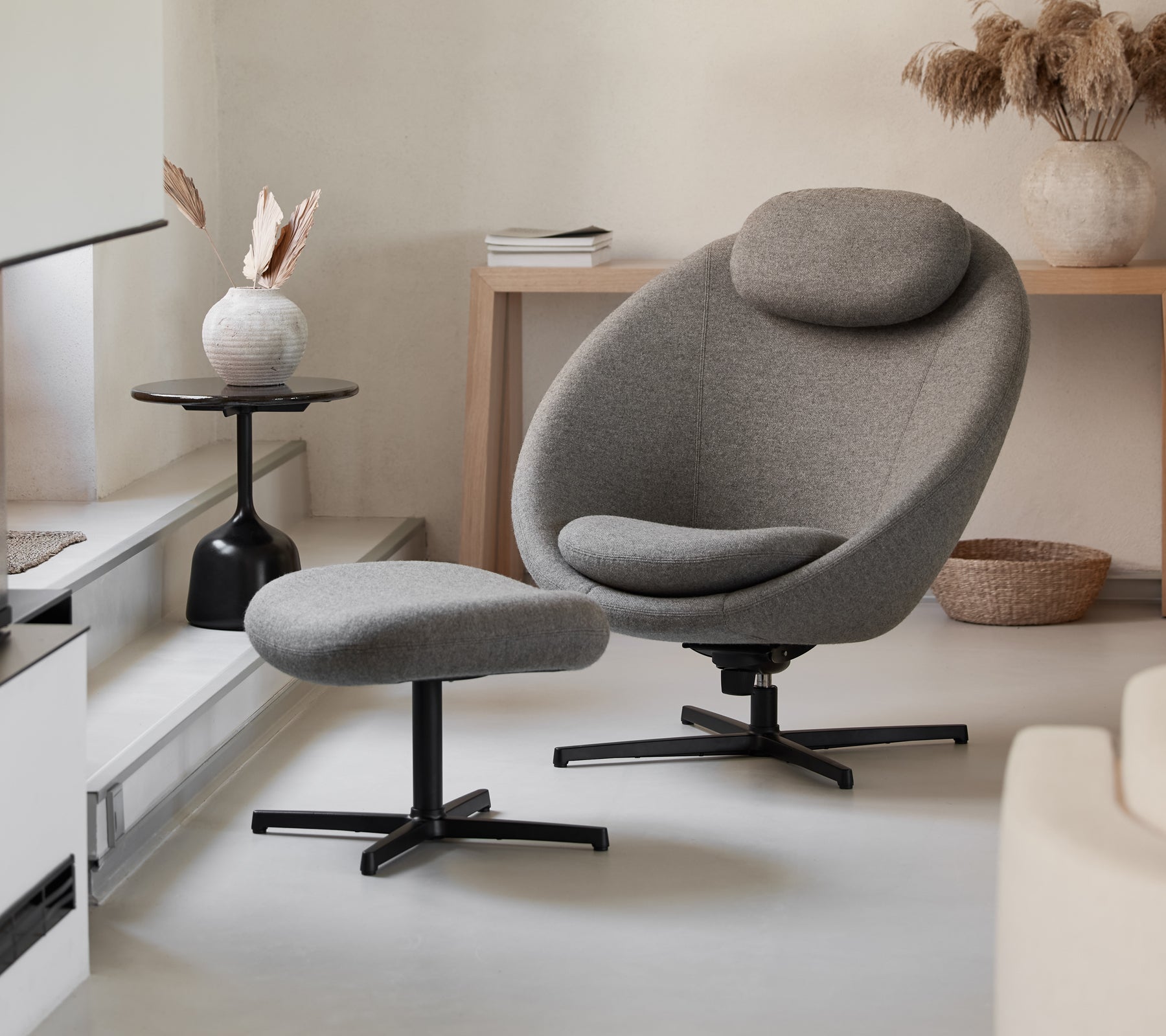Stilfuld grå stol med matchende ottoman, der har et strømlinet design og komfortable kurver, suppleret af moderne dekorationselementer.