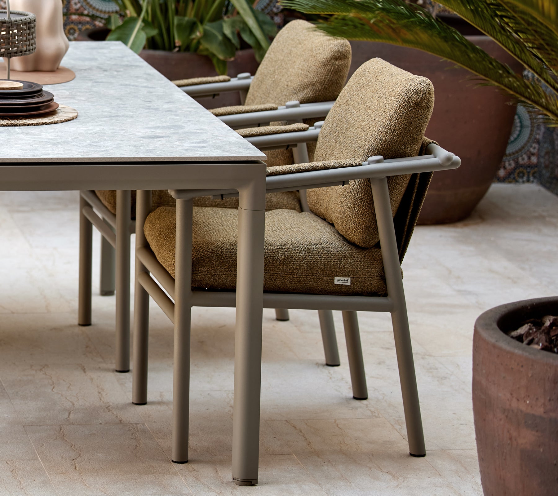 To spiseborde med bløde puder, der har et moderne design med robuste ben, placeret ved siden af et bord med dekorative genstande.