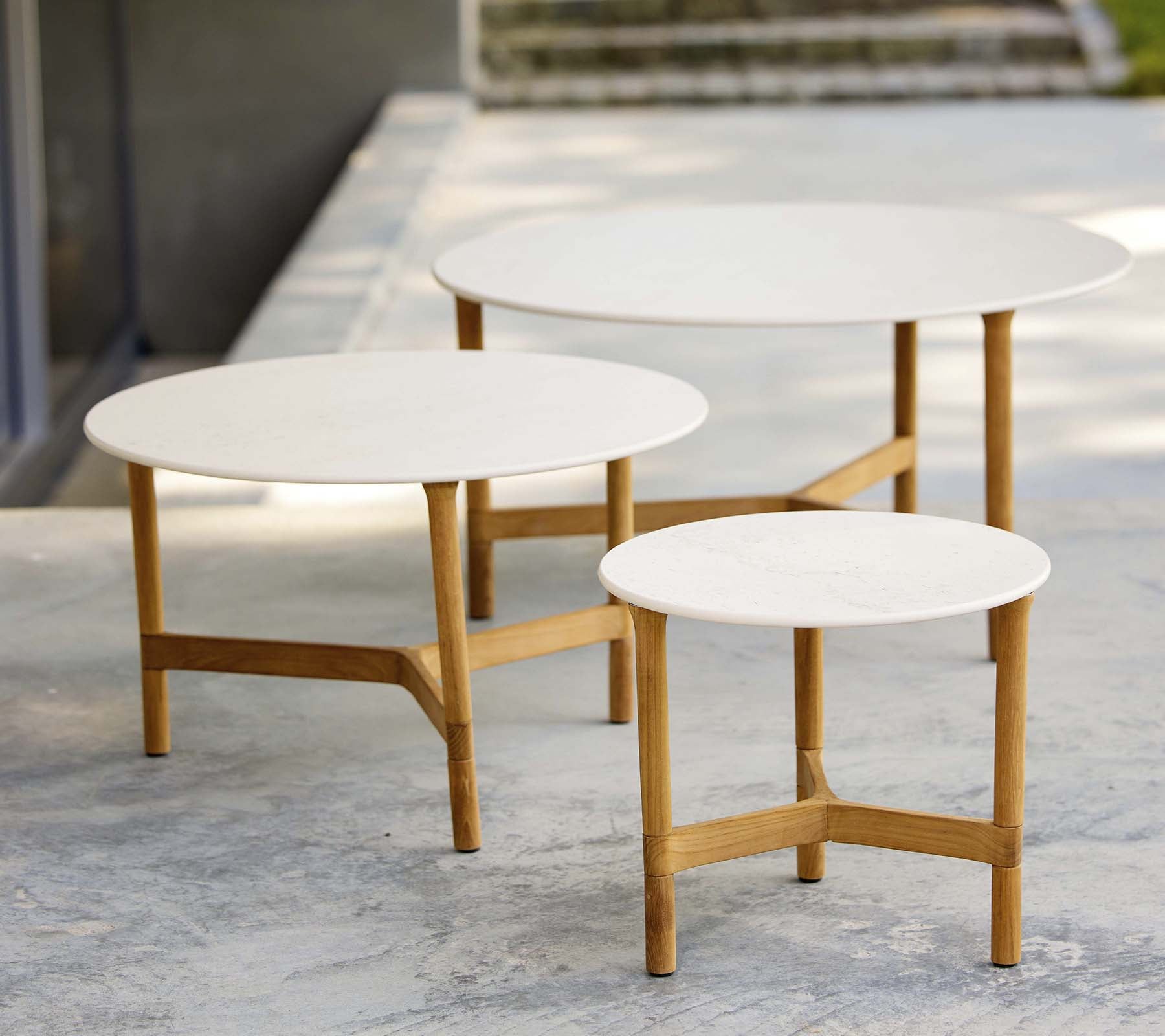 Tre moderne sofaborde i forskellige størrelser med hvide toppe og træben, der udviser et stilfuldt og minimalistisk design.