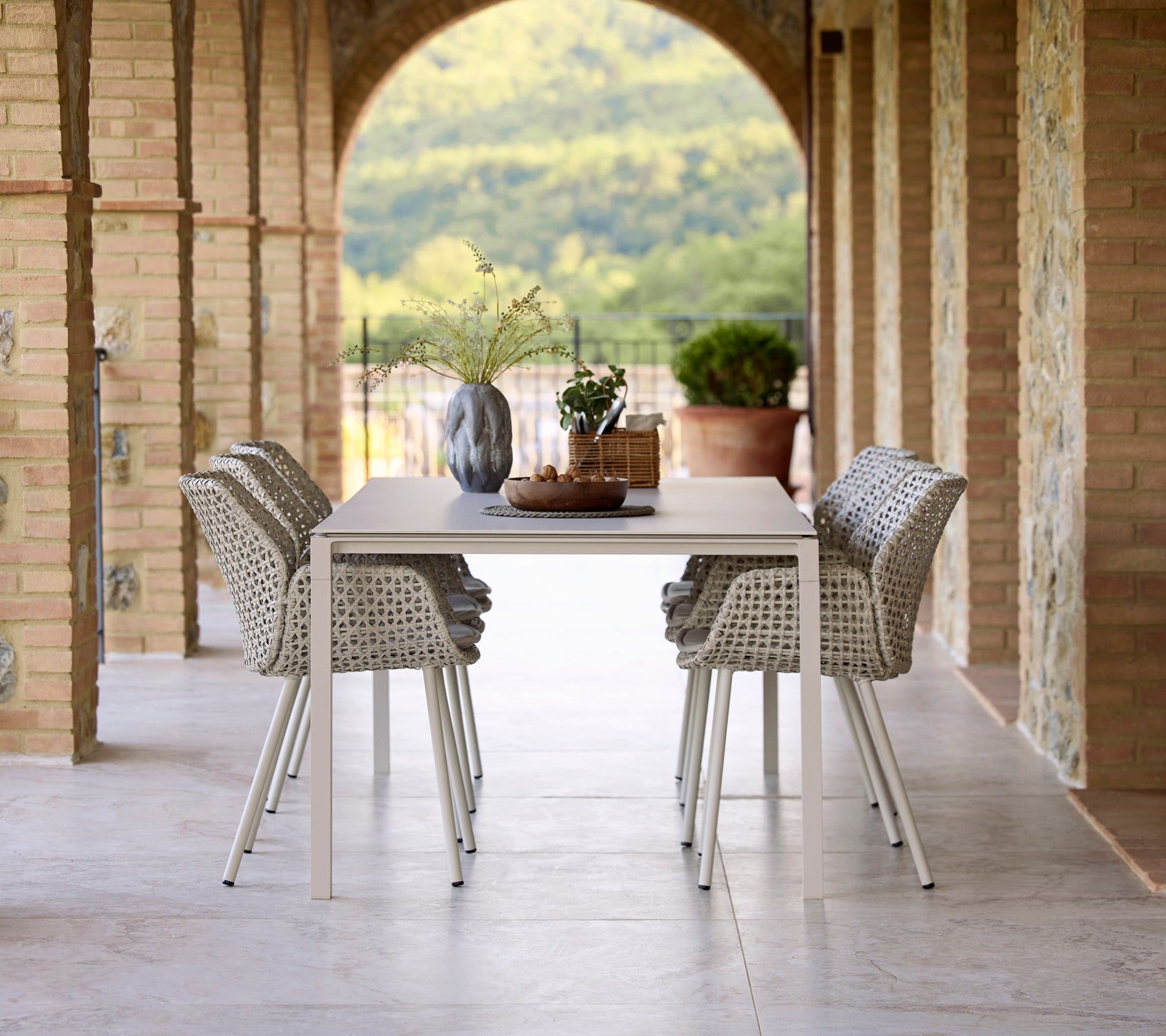 Elegant spisebordslayout med et Pure sand spisebord omgivet af Vibe spiseborde, akkompagneret af en vase og dekorative elementer.