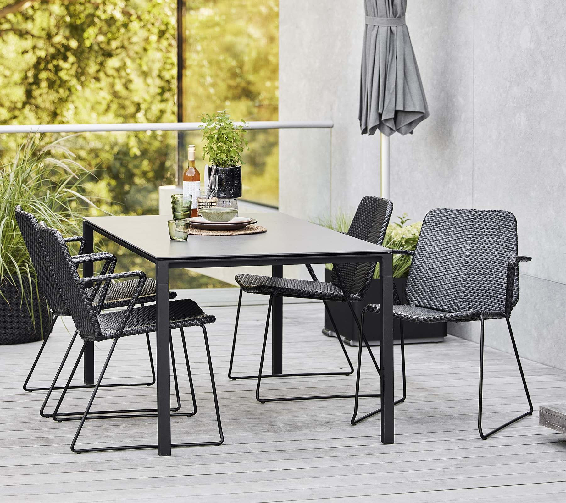 Et moderne bord omgivet af stilfulde stole, suppleret af dekorative genstande og grønne planter i baggrunden.