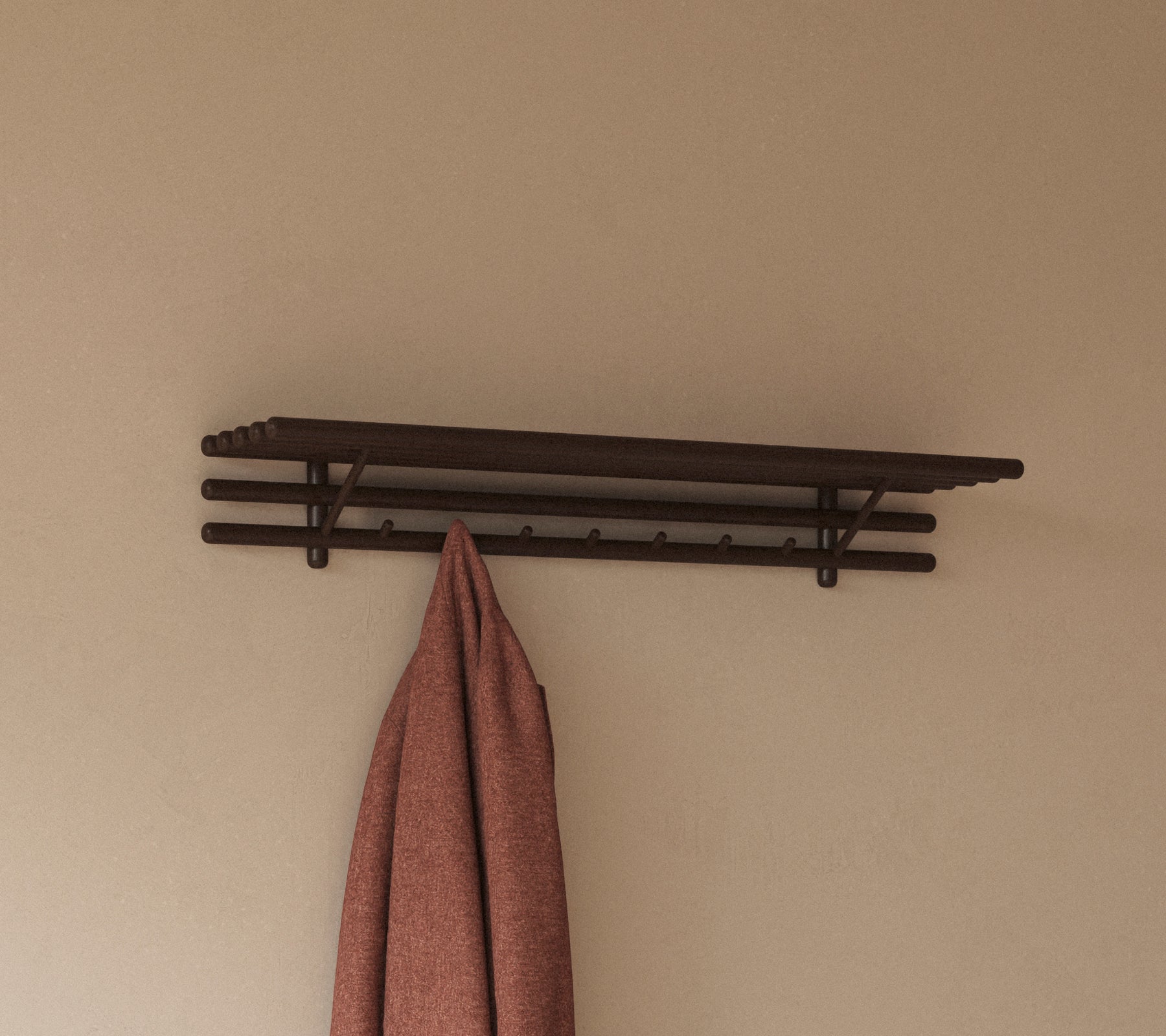 Et minimalistisk hylde med flere kroge, der holder et hængende klæde, designet til praktisk opbevaring og organisering.