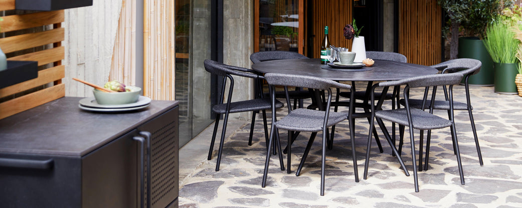 A modern dining set featuring a round black table and matching chairs, accompanied by plates and bowls for a stylish dining experience.