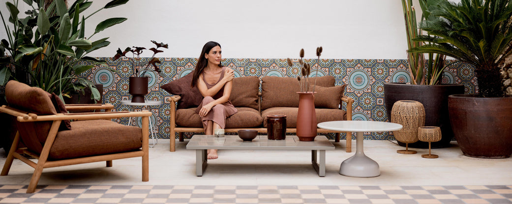 Et stilfuldt loungeområde med en komfortabel sofa, moderne kaffebord, dekorative vaser og frodig grønne planter for en indbydende atmosfære.