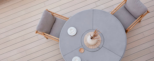 Rund spisebord med bløde siddepladser, suppleret af dekorative tallerkener og en midterdekoration. Simpelt, elegant design.