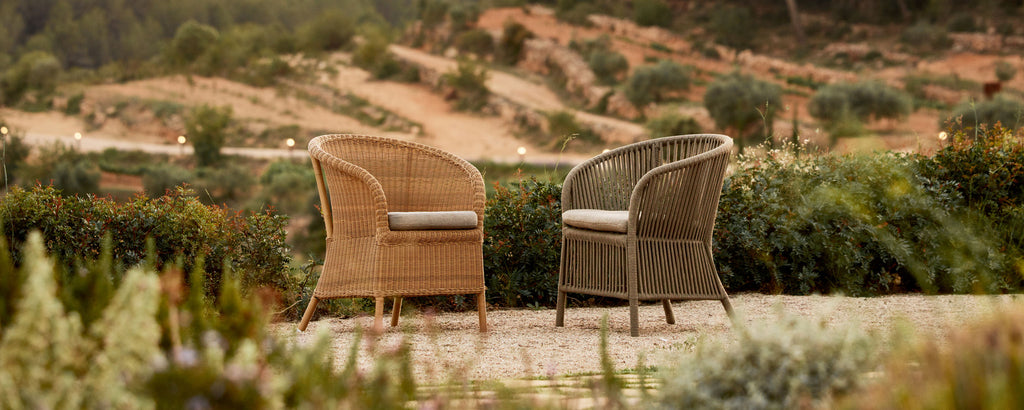 Two stylish wicker chairs with cushions positioned in a scenic landscape, inviting relaxation and conversation.