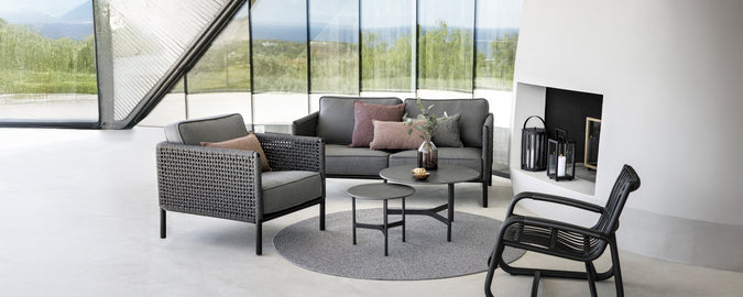 Moderne loungeområde med en grå sofa, sort lænestol og rundt sofabord.