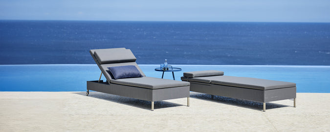 Grå lounge stol og chaiselong ved en pool med udsigt til havet.
