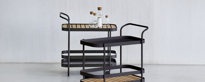 Moderne sort serveringsvogn med brun bakke i en stilfuld loungeindretning.