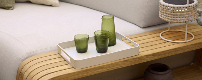 Moderne loungeindretning med grønt glas på en hvid bakke.