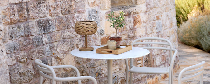 Moderne udendørs miljø med hvidt bord, hvide stole og brune dekorative elementer.