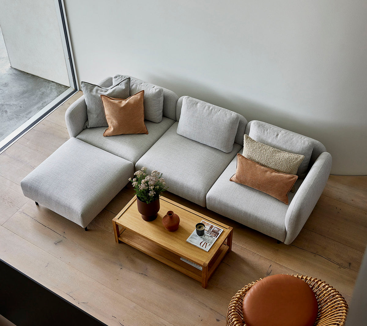 En stilfuld lysegrå sektion sofa med puder, parret med et rundt trækaffebord og en rund siddeplads, der skaber en hyggelig atmosfære.