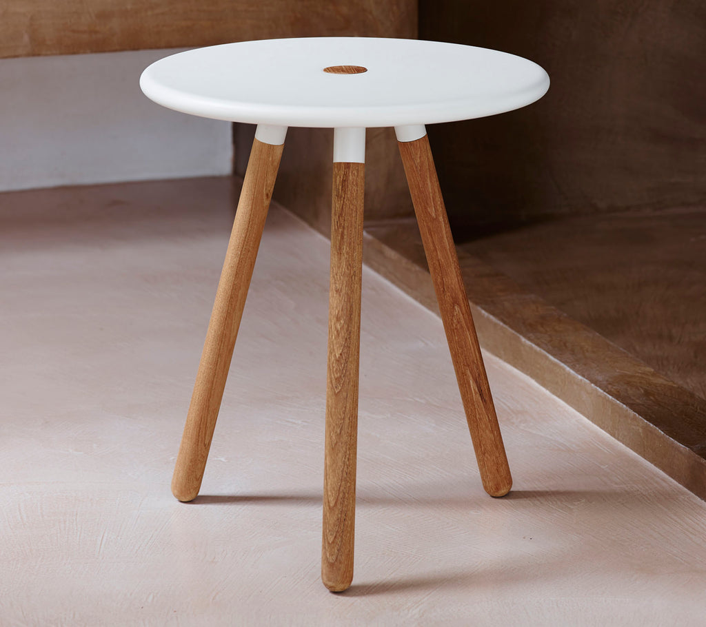 Et moderne rundt bord med en hvid top og naturlige træben, der har et lille hul i midten for designinteresse.