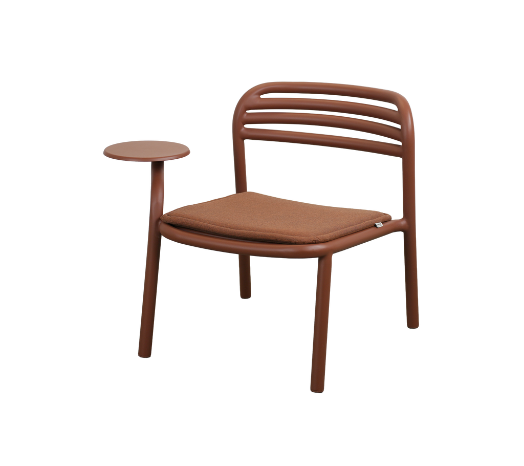 Moderne stol i ørkenrød med et lille sidebord.