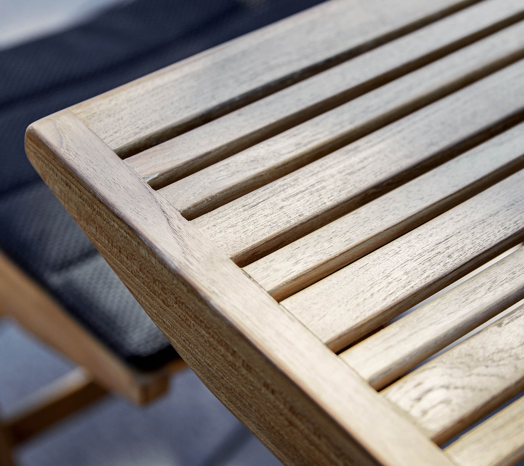 Klausyring af en træbordkant med lamel-design, der viser det naturlige korn og tekstur i træet.