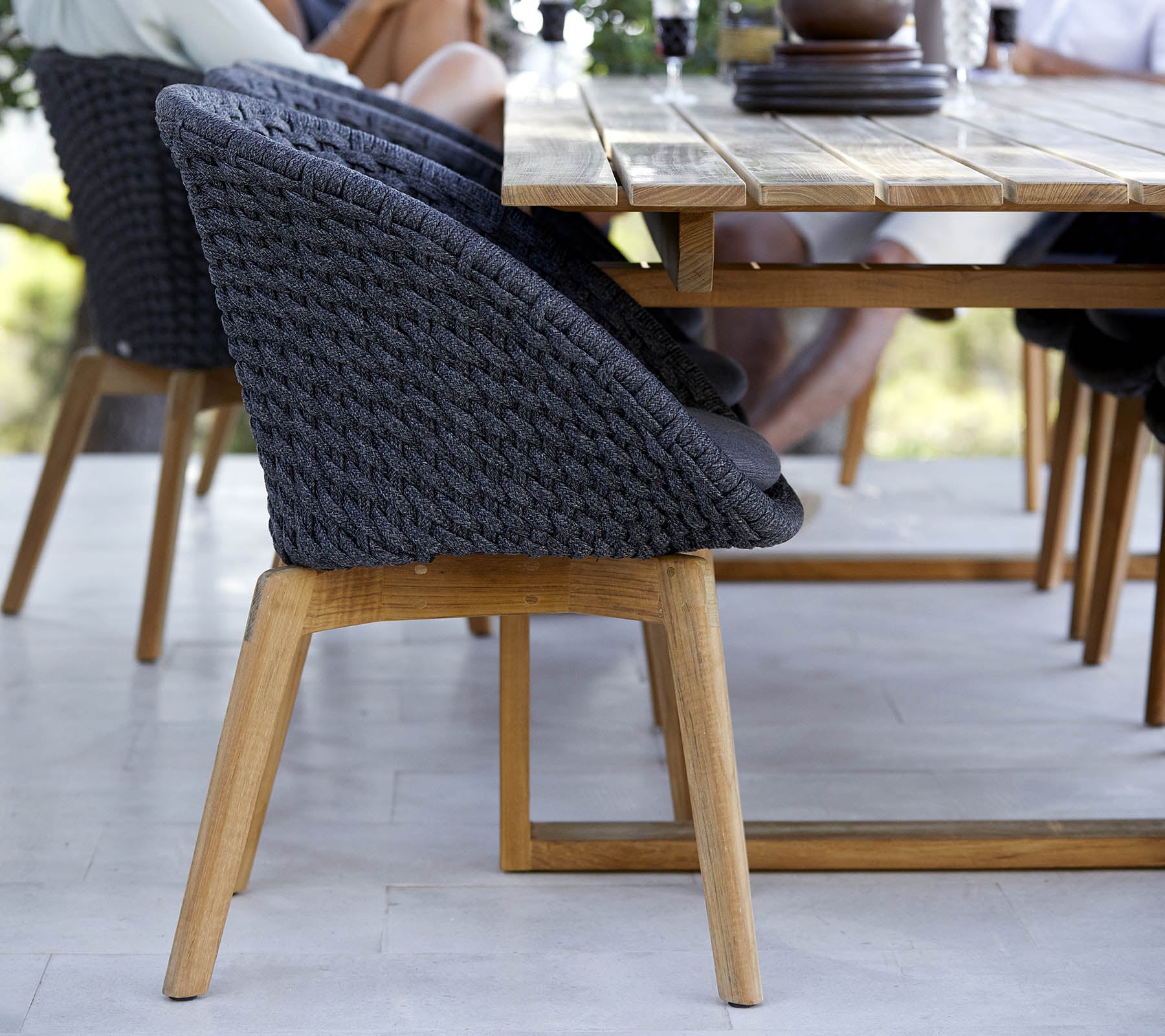 Stilfuld vævet stol med en træbund, placeret ved siden af et bord, der viser et moderne design perfekt til samlede rum.