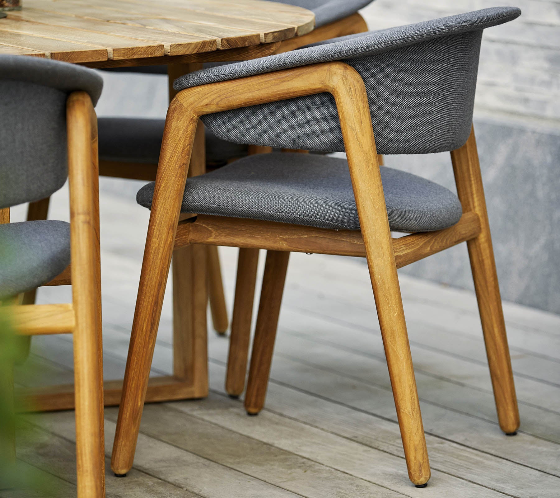 Stilfuld træstol med grå polstret sæde og ryg, parret med et rundt bord i moderne design.