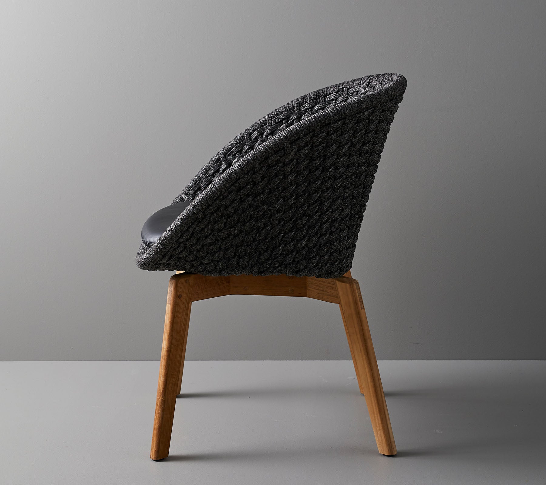 Stilfuld stol med vævet rygstøtte og træben, der tilbyder et moderne design ideelt til nutidige rum.