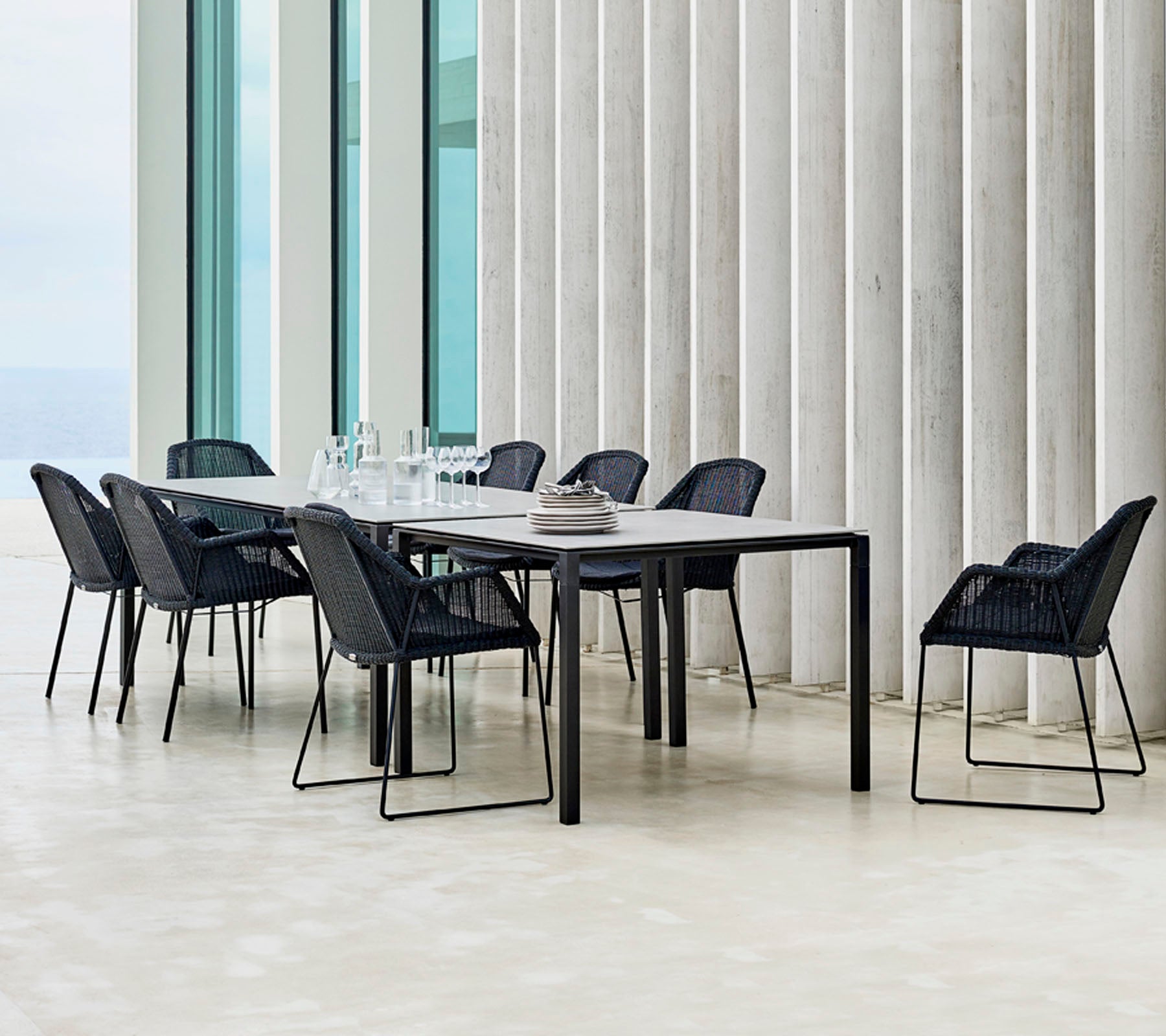 Et moderne spisestuesæt med sorte stole arrangeret omkring det, der har minimalistiske designelementer og en stilfuld borddækning.
