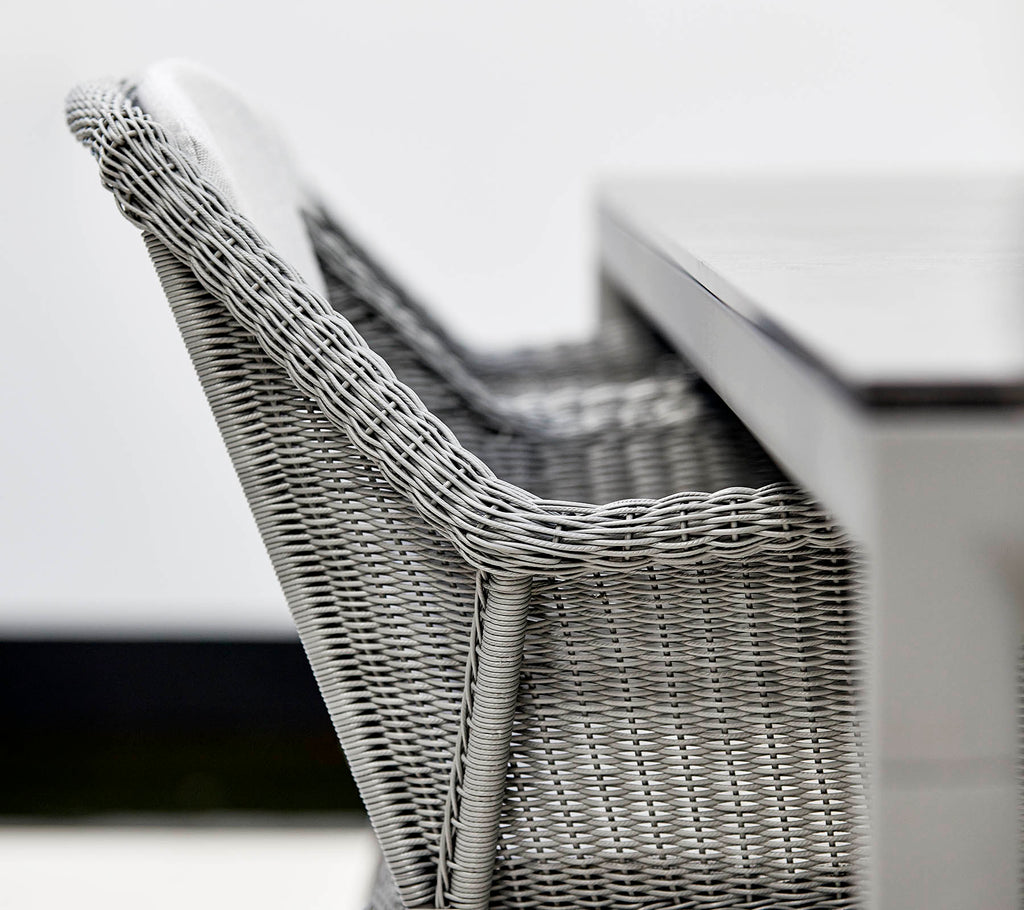 Et close-up af en stilfuld grå kurvestol ved siden af et strømlinet bord, der viser moderne design og teksturer.