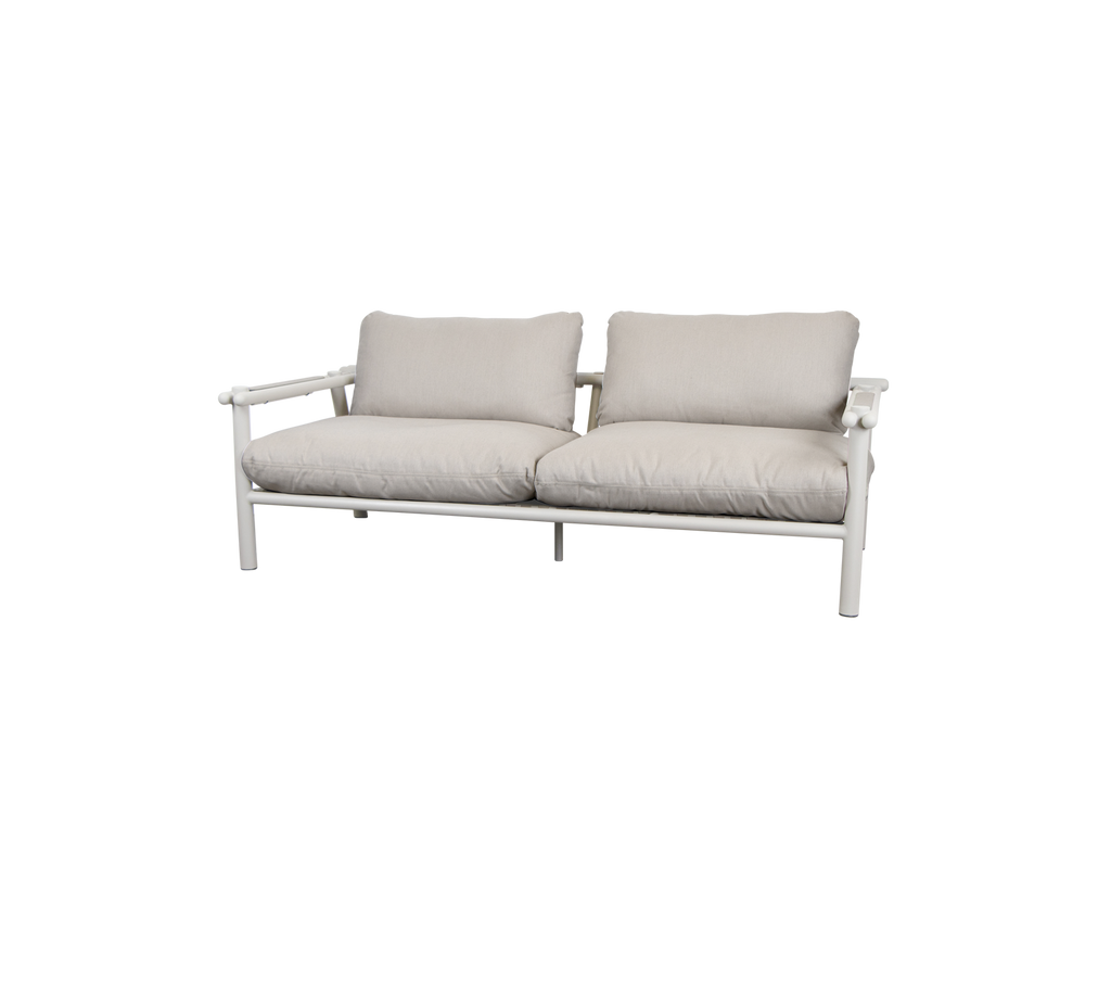 Moderne sofa med sandfarvede puder og en lys ramme.