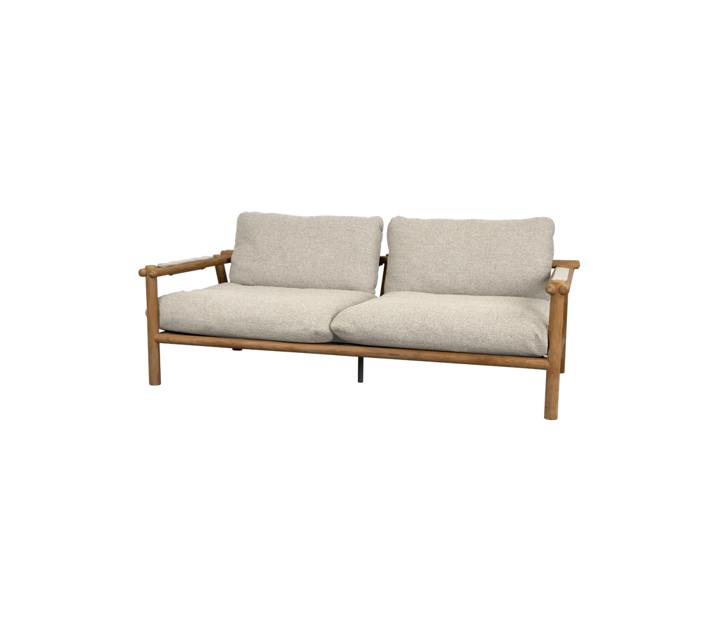 Moderne teaksofa med sandsfarvede puder.