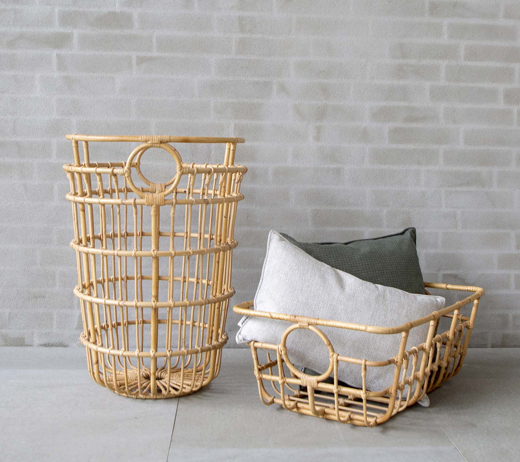 Moderne vævede kurve med grå og grønne puder i et minimalistisk miljø.