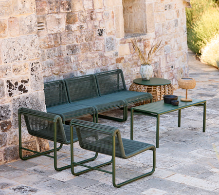 Moderne grøn sofa og stole med et matchende bord i en afslappet loungeindstilling.