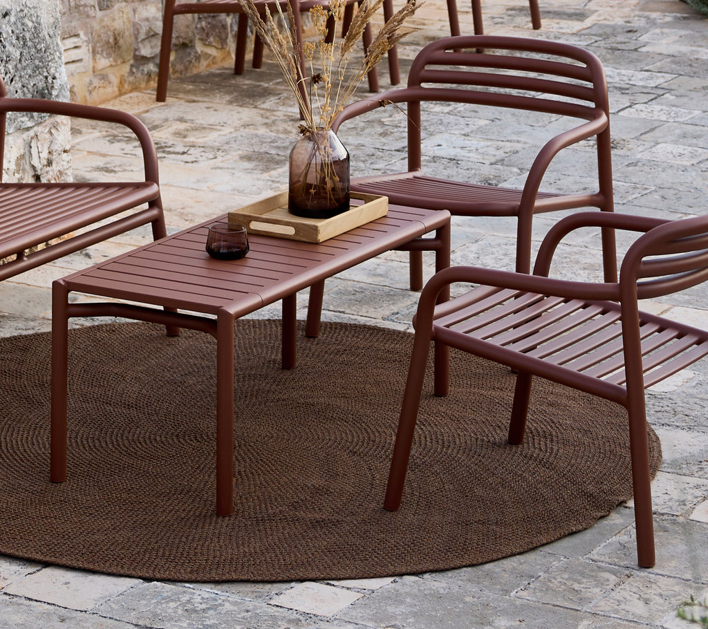 Minimalistisk brun bord og stole arrangeret i en loungeindstilling.